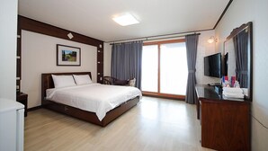 Una habitación de hotel con cama, escritorio, silla, televisor y ventana con cortinas.