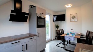 A modern kitchen with a built-in oven and a dining area with a table set for four. - Overath Luxus Apartments (Overath)