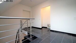 A modern interior with a staircase, a door, and a hallway. - Overath Luxus Apartments (Overath)