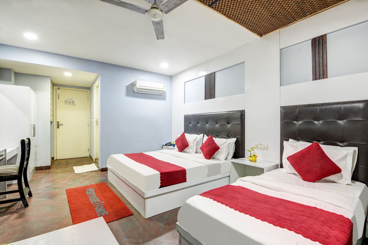 A hotel room with two beds, a ceiling fan, an air conditioning unit, and a red rug.