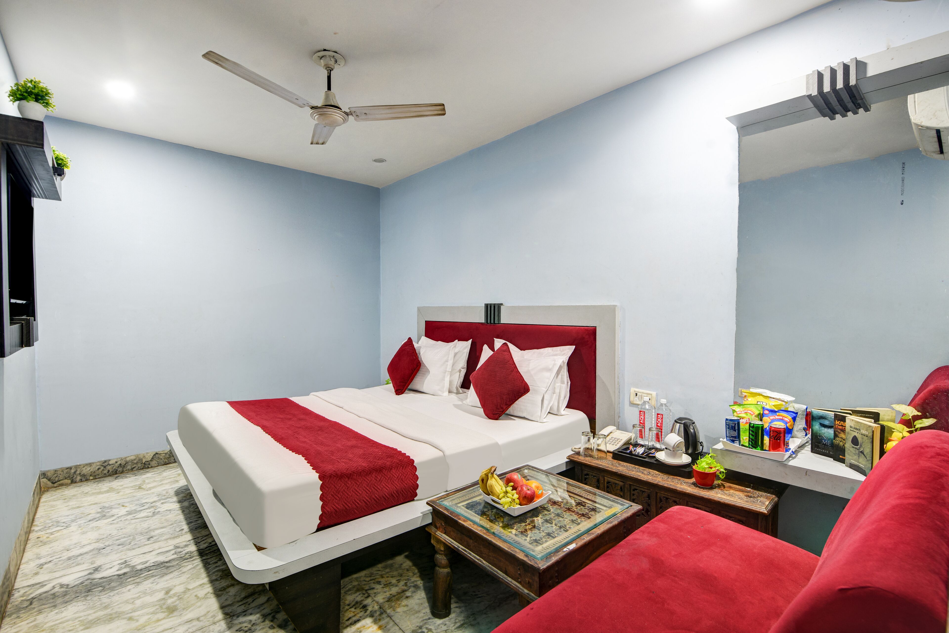 Un dormitorio con cama, mesita de noche y una pequeña mesa con aperitivos.