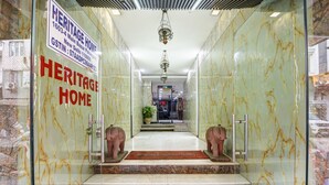 Entrada de hotel con suelo de mármol, dos estatuas de elefantes y un candelabro.