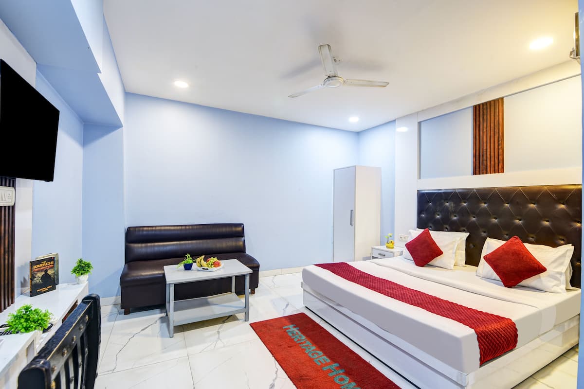 A modern hotel room with a bed, a sofa, a small table, and a TV.