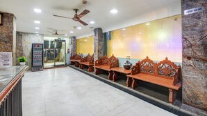 Un hall de hotel con paredes de mármol, una recepción y una fila de bancos de madera.