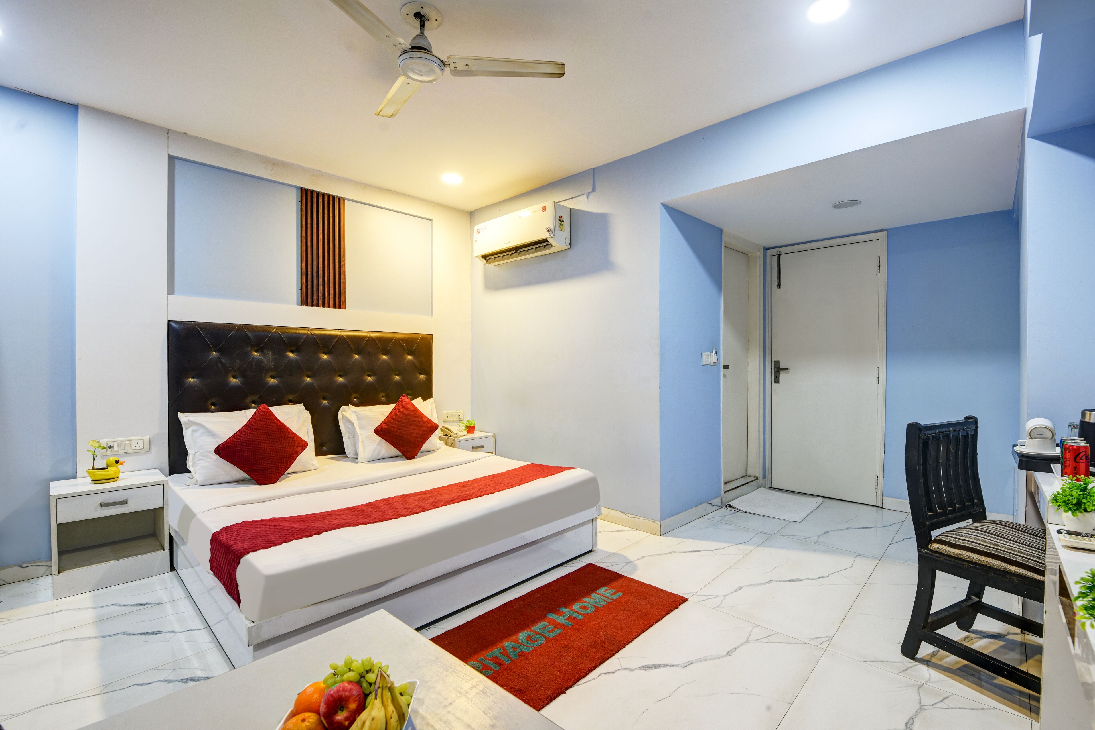 A modern hotel room with a large bed, a desk, a chair, and a ceiling fan.