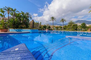 Una piscina al aire libre, una piscina climatizada, tumbonas