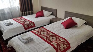 Two twin beds with white bedding and red decorative pillows, each with a folded towel at the foot of the bed. - Bal-Meyir Hotel Almaty (Almaty)