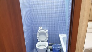 A small bathroom with a toilet, a blue trash bin, and a white sink. - Bal-Meyir Hotel Almaty (Almaty)