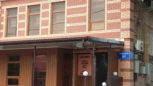 A brick building with a wooden facade, a covered entrance, and a sign indicating it is a motel and hostel. - Bal-Meyir Hotel Almaty (Almaty)