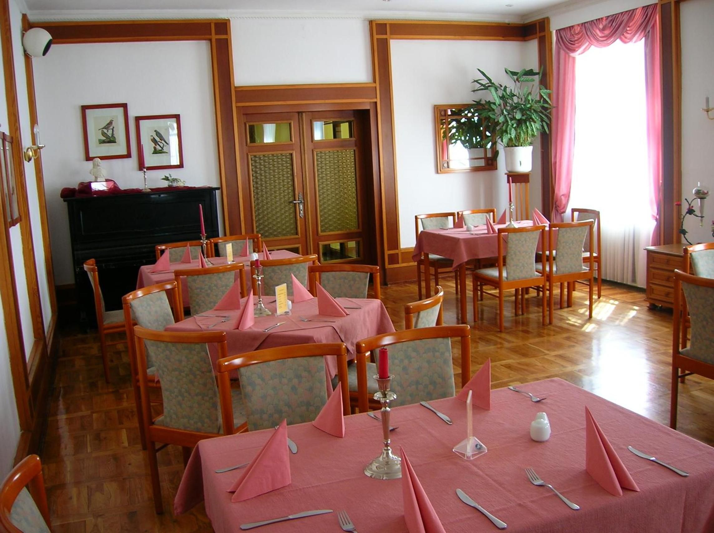 Un comedor con mesas y sillas de madera, una chimenea y cuadros en las paredes.