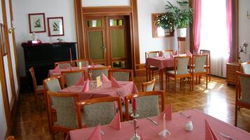 Un comedor con mesas y sillas de madera, una chimenea y cuadros en las paredes.