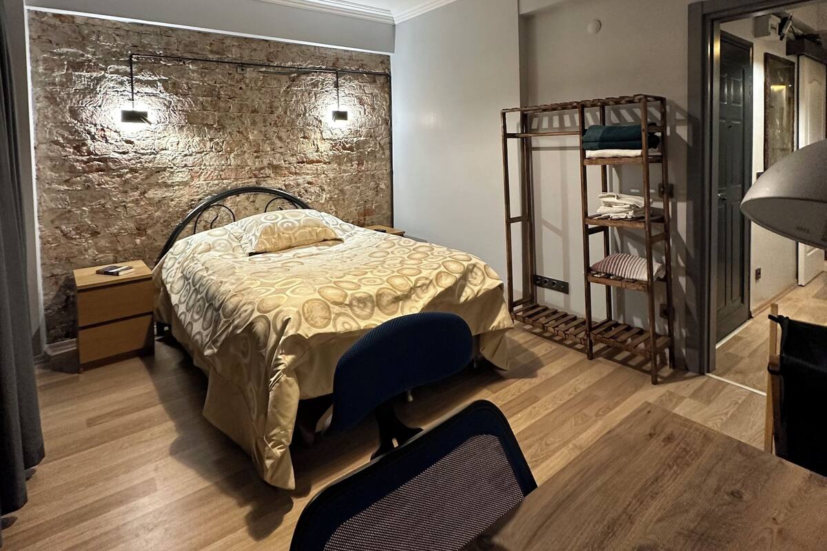 Un dormitorio con cama, escritorio, silla, armario e iluminación colgante.