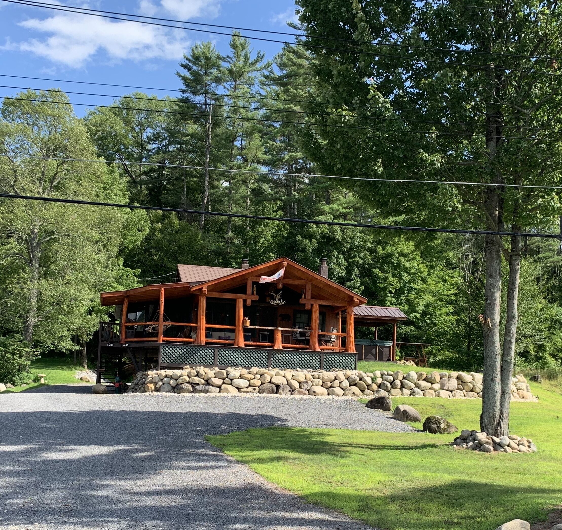 A rustic cabin with a stone foundation, wooden exterior, and a porch with outdoor seating.