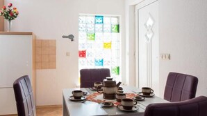 Un comedor con una mesa dispuesta para cuatro, sillas, una cafetera y tazas.