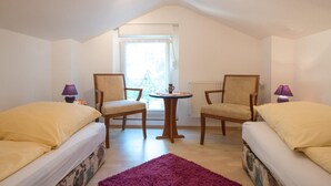 Una habitación pequeña y acogedora con dos camas individuales, una mesa redonda, dos sillas y una ventana con vistas.