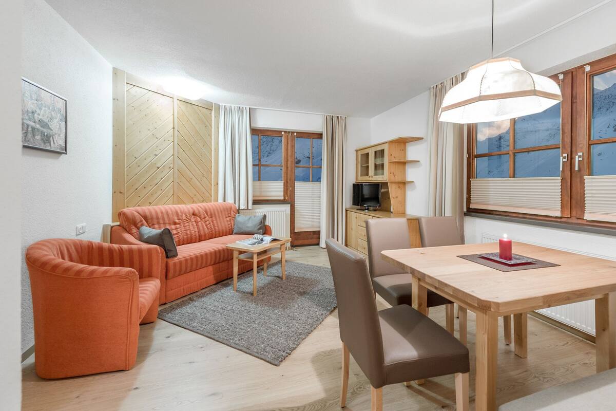 A cozy living room with a sofa, a dining table, and a TV.