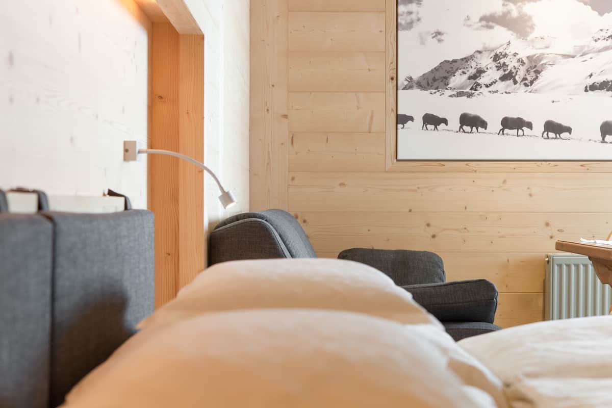 A cozy room with a wooden wall, a mounted picture of sheep on a snowy mountain, and a radiator.