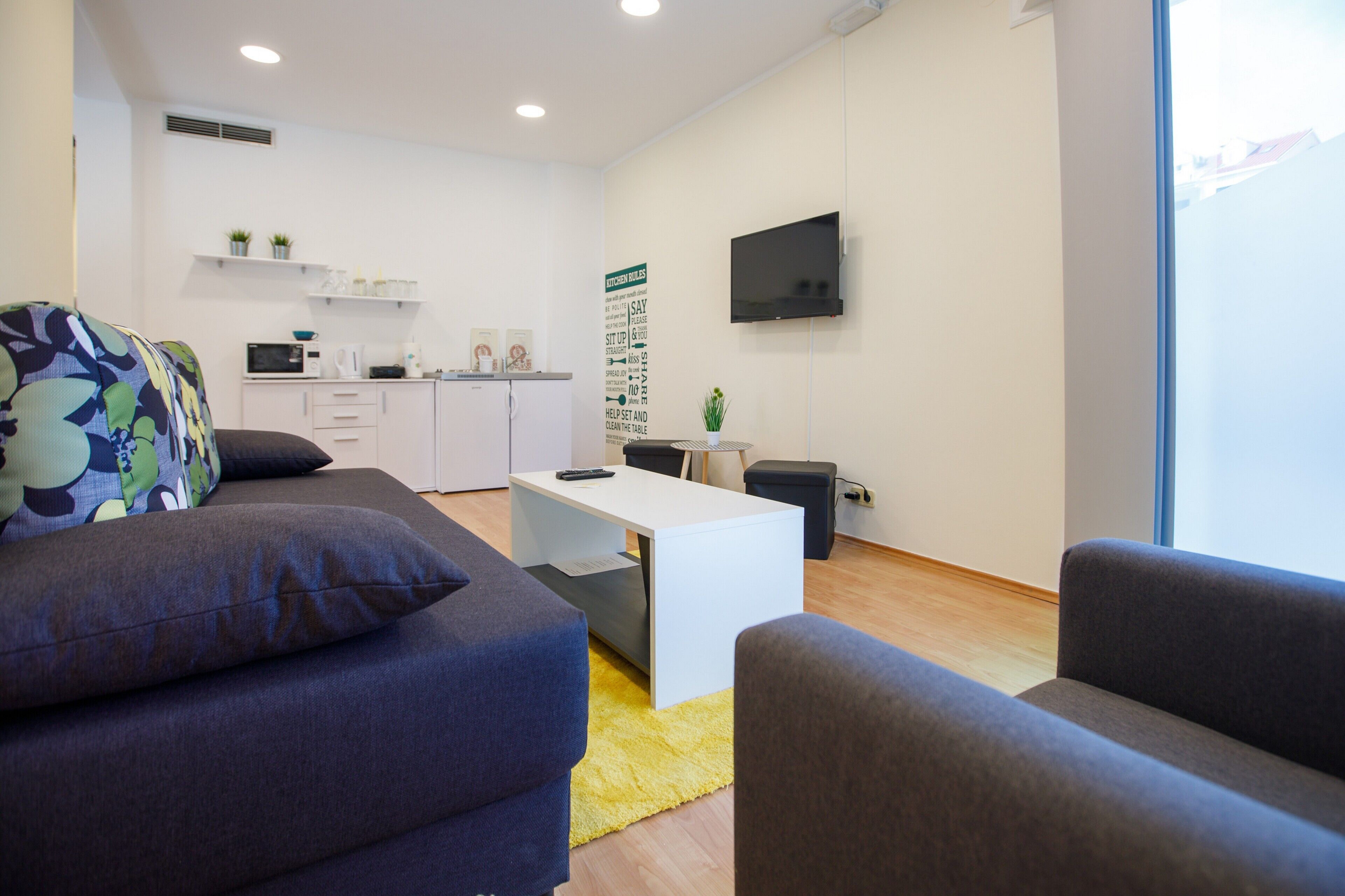 A modern living room with a sofa, a coffee table, and a TV mounted on the wall.