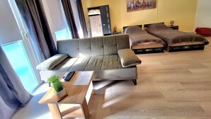 Un saló modern amb un sofà, una taula de centre i un llit amb calaixos d'emmagatzematge.