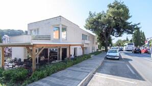 Un edifici de dues plantes amb una zona d'estar exterior coberta i un pàrquing.