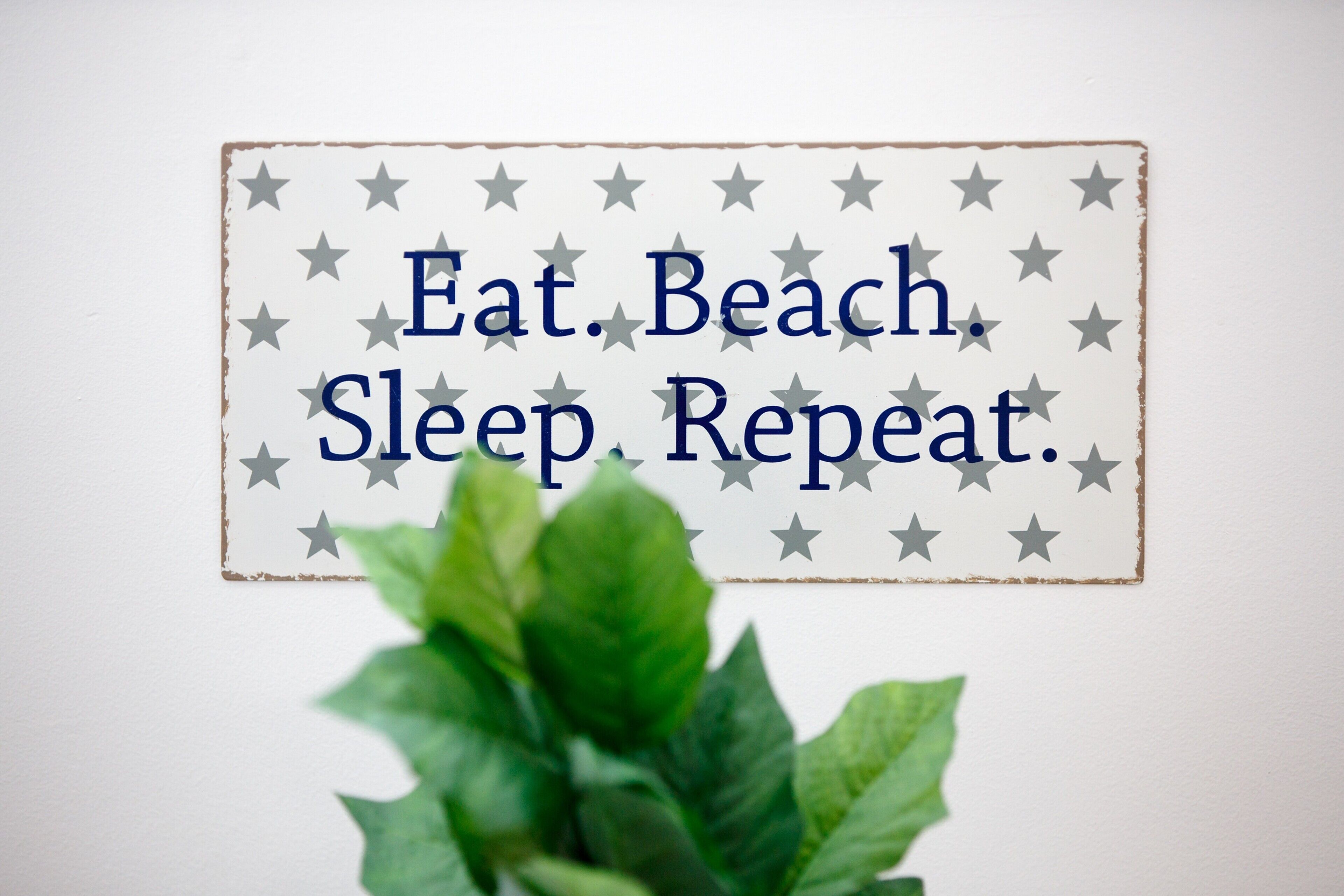 A sign with the text "Eat. Beach. Sleep. Repeat." surrounded by stars.