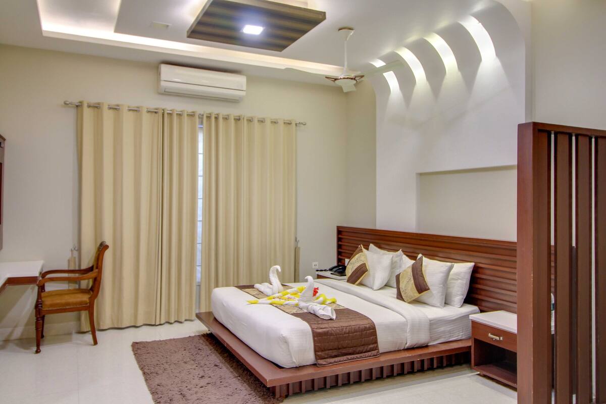 A hotel room with a bed, a desk, a chair, and a wardrobe.