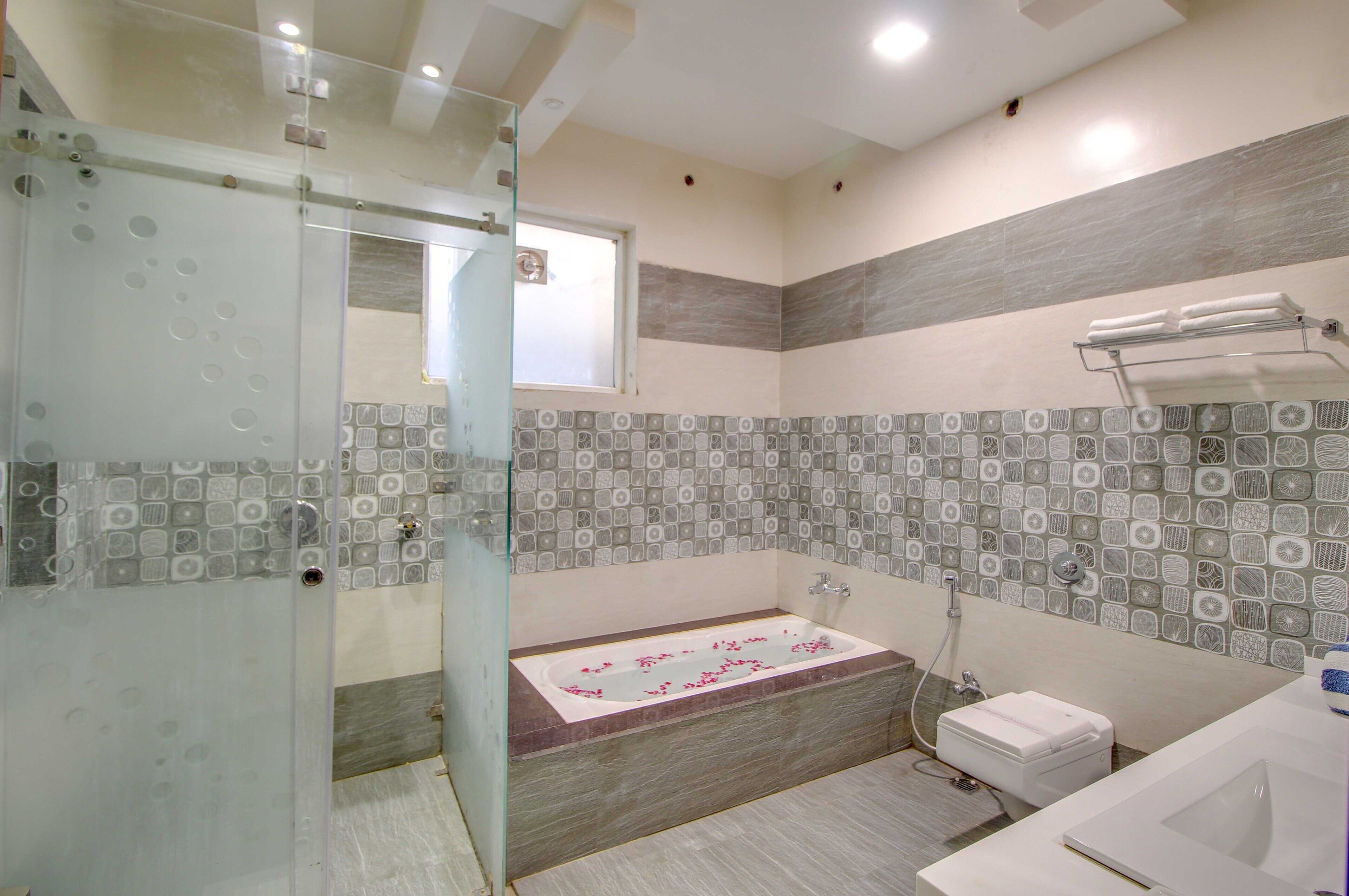 Un baño moderno con cabina de ducha de vidrio, bañera independiente y un inodoro separado.