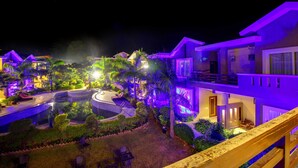 A resort with multiple buildings, a swimming pool, and well-lit pathways. - Maulik Mansion Resort (Ramnagar)