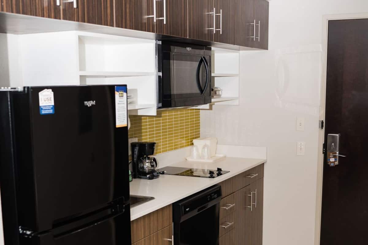 A kitchen with a black refrigerator, a microwave, a coffee maker, and a dishwasher.