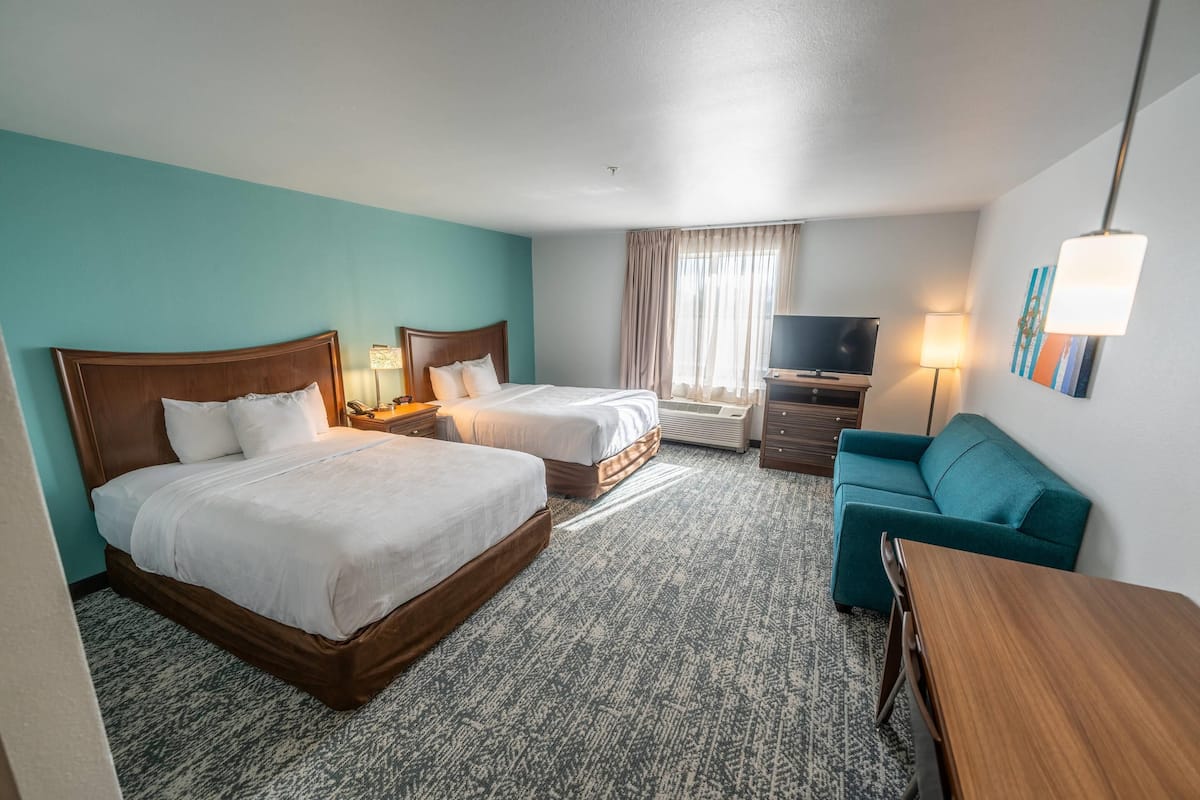 A hotel room with two beds, a TV, a desk, and a couch.