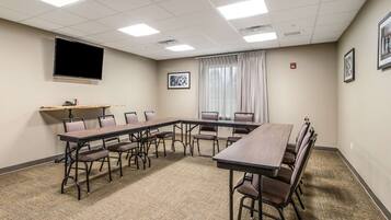 A conference room with a long table, chairs, a flat-screen TV, and framed pictures on the walls.