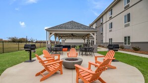 An outdoor patio with Adirondack chairs, a fire pit, and a covered seating area with a ceiling fan. - MainStay Suites at Discovery Park of America (Union City)