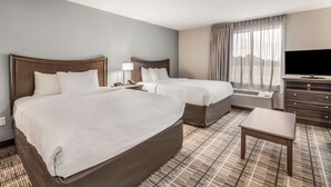 A hotel room with two beds, a TV, a desk, and a view of the city. - MainStay Suites at Discovery Park of America (Union City)