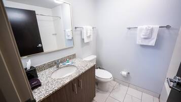 Un baño con lavamanos doble, inodoro, toallero y espejo.
