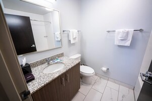 Un baño con lavamanos doble, inodoro, toallero y espejo.