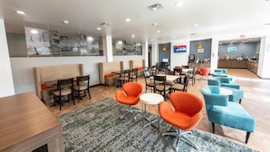 A modern hotel lobby with seating areas, a reception desk, and a large TV screen. - MainStay Suites at Discovery Park of America (Union City)