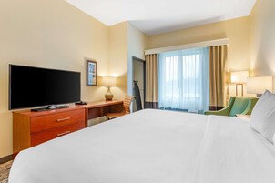Habitación de hotel con una cama grande, televisión de pantalla plana, escritorio con lámpara y una silla.