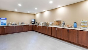 A spacious, well-lit room with a long counter featuring various food and beverage dispensers, a coffee machine, and a hot water station. - Comfort Inn & Suites West Des Moines (West Des Moines)
