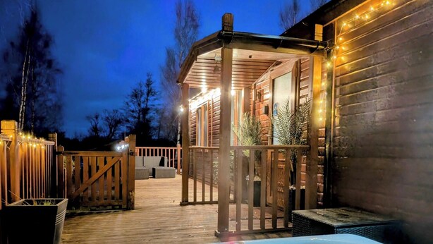 A wooden cabin with a hot tub, deck, and outdoor seating area. - Felmoor Park Northumberland Lodge With Hot Tub - 4 (Morpeth)