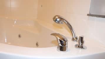 Una bañera blanca con detalles cromados en un baño.