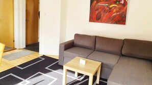 A living room with a brown sofa, a small wooden table, and a colorful abstract painting on the wall. - Struer Town Apartment (Struer)