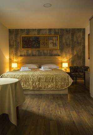 A neatly arranged hotel room with a large bed, two bedside lamps, a chair, and a small table.