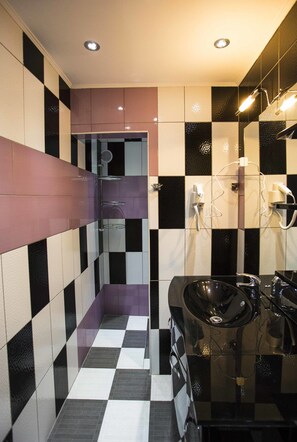A modern bathroom with checkered floor tiles, a black sink, and a mirror with a light fixture above it.