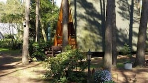 A forested area with a small wooden structure, possibly a cabin or shed, surrounded by trees and potted plants. - Nepumuk-Ranch (Arendsee)