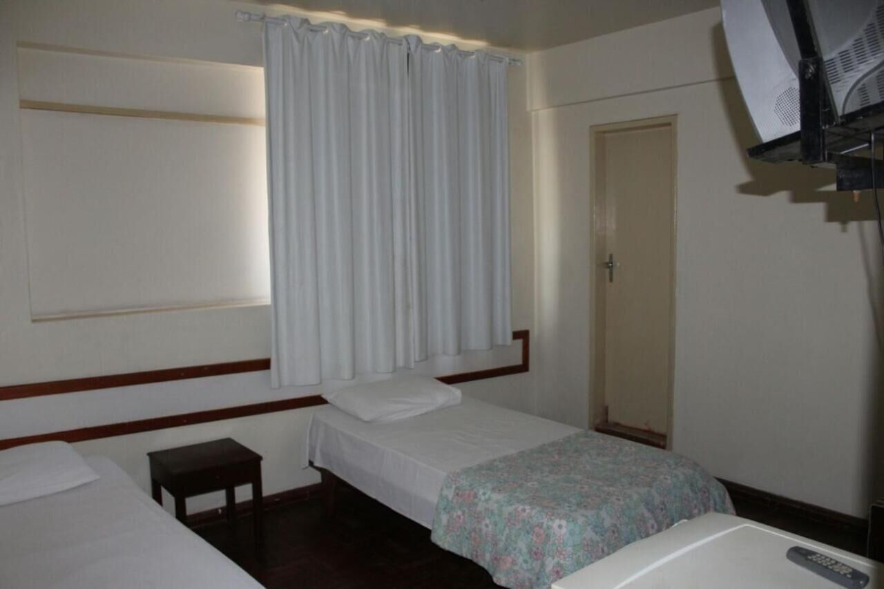 Ein Hotelzimmer mit zwei Einzelbetten, einem kleinen Tisch, einer Tür und einem Deckenventilator.