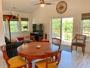 A dining area with a wooden table and chairs, a television, and a large clock on the wall.
