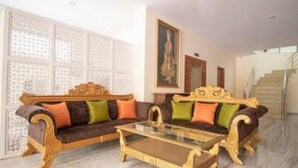 A room with a brown sofa set, a glass coffee table, and a staircase in the background. - Hotel Golden Ram Vilas (Jaipur)