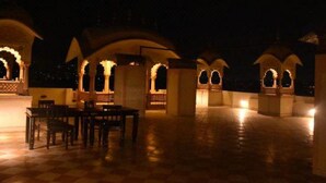A courtyard with traditional arches and a dining area with tables and chairs. - Hotel Golden Ram Vilas (Jaipur)