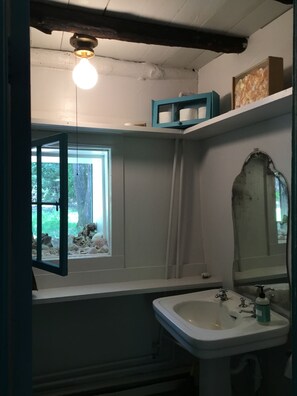 Bathroom with a sink, mirror, and window offering a view of trees and rocks.
