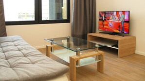 A modern living room with a sofa, a glass-top coffee table, and a wooden TV stand. - Quality Apartment Miletičova (Bratislava)